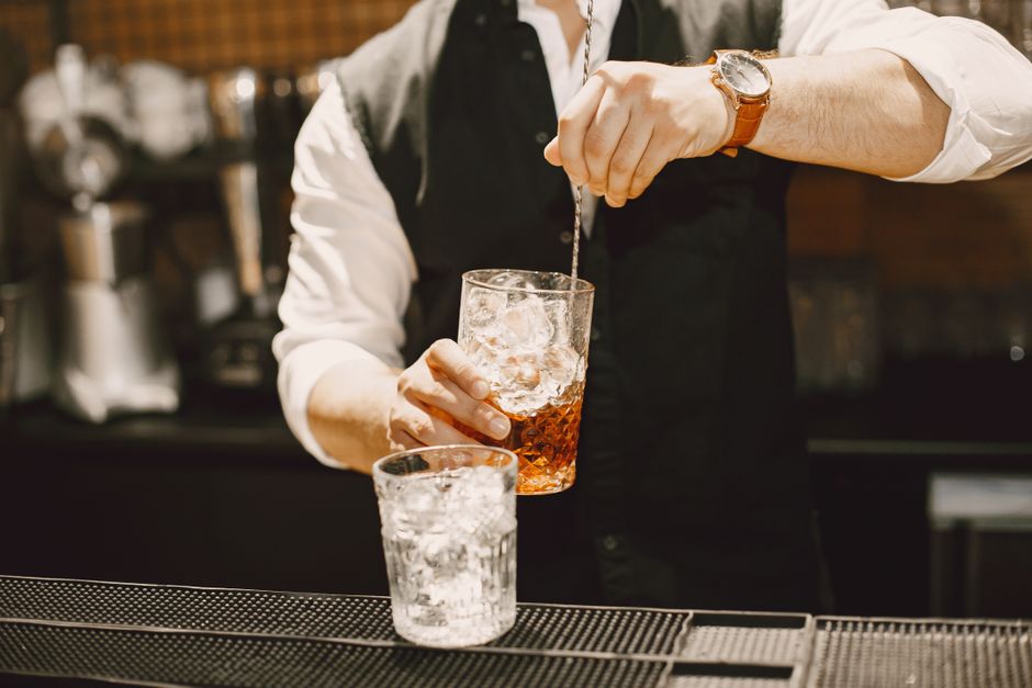 Bartender rör en drink på is i ett blandningsglas med barsked