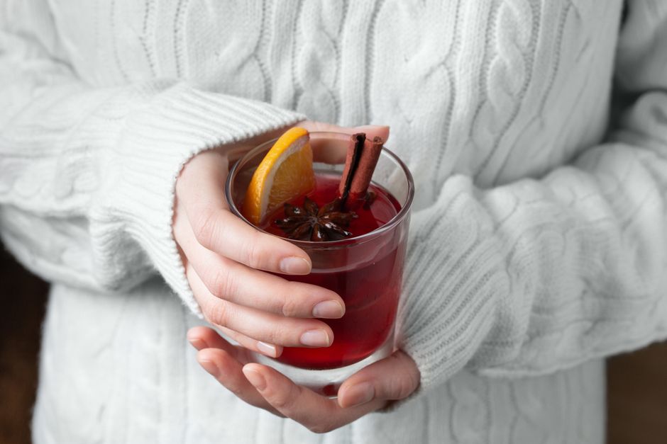Glas med varm glögg garnerat med apelsinskiva, kanelstång och stjärnanis