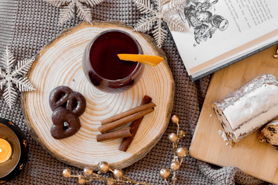 Top view of a cozy winter setup with mulled wine, cinnamon sticks, and holiday treats, perfect for festive moods.